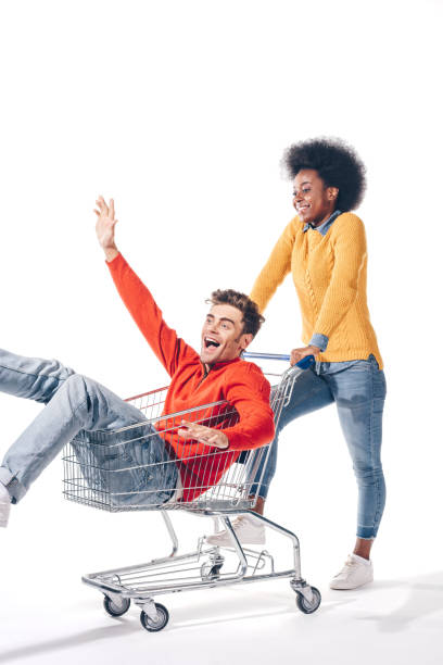 istock multicultural couple having fun with shopping cart, isolated on white 1181641062