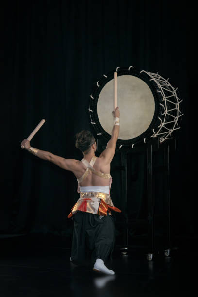 taiko-schlagzeuger schlägt die große trommel auf der bühne auf einem schwarzen hintergrund, rückansicht. - taiko drum stock-fotos und bilder