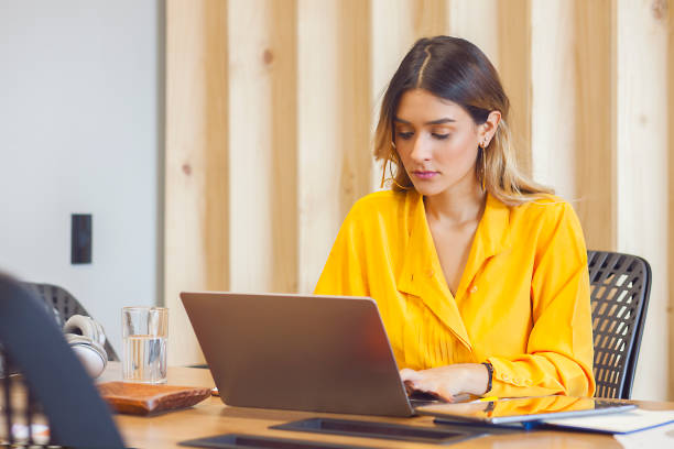 istock Young woman of latin ethnicity, inside an office sitting looking at the computer while typing. 1181644944