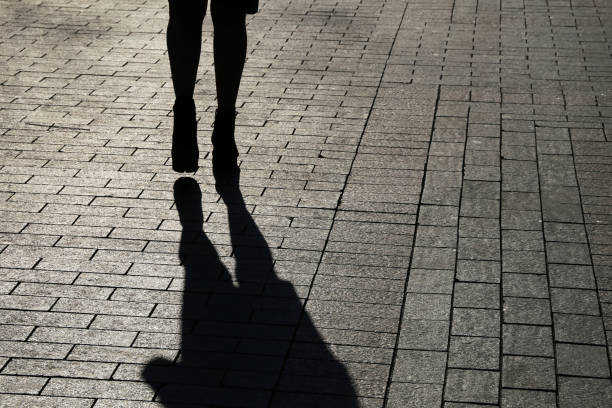 Black silhouette and shadow of lonely woman walking down on a street Concept of loneliness, crime, dramatic human life stalker stock pictures, royalty-free photos & images