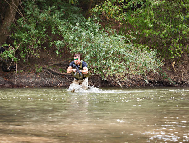 istock One day commando - wades through the water with a rifle 1181646603