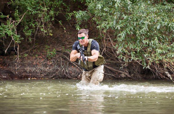 istock One day commando - wades through the water with a rifle 1181646842