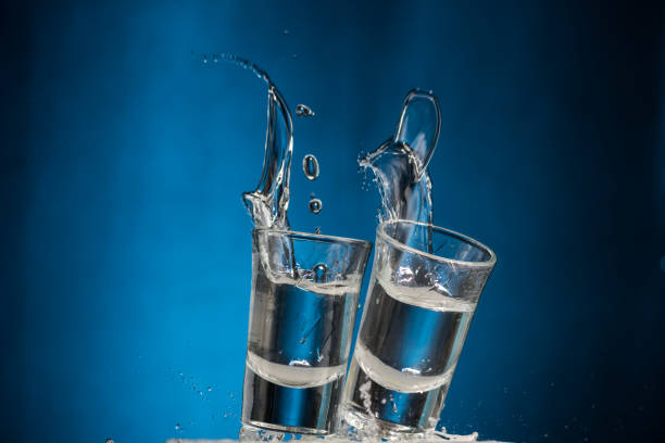 istock falling glasses with vodka and spray on a blue background 1181651963