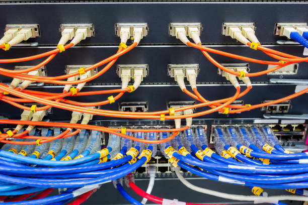 cable network , fiber optic cable connect to switch port in server room stock photo