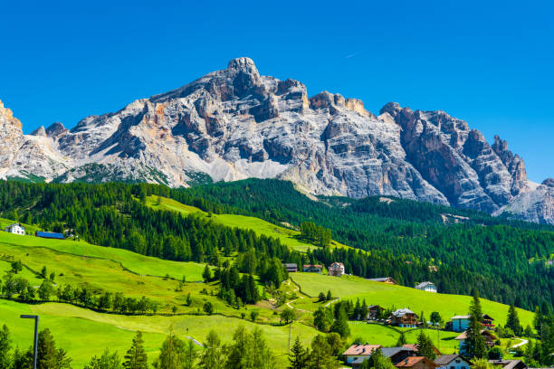 istock Small town on green alpine meadows with huge mountains on the background. 1181652186