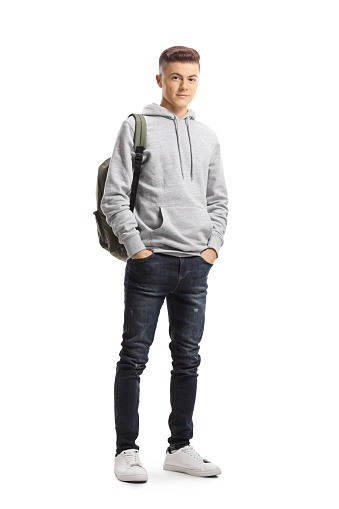 Full length portrait of a teenage schoolboy posing with hands in pockets isolated on white background