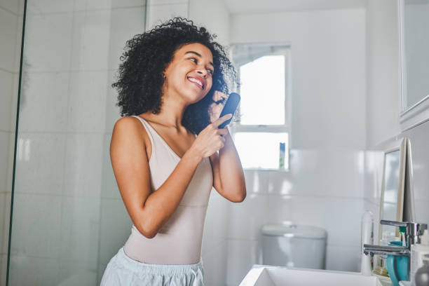 Queens wake up in the morning and fix their crowns Shot of an attractive young woman brushing her hair inside her bathroom at home brushing hair stock pictures, royalty-free photos & images