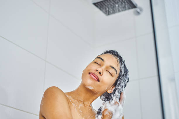 My hair feels healthier and stronger already Shot of an attractive young woman washing her hair with shampoo in the shower at home natural hair stock pictures, royalty-free photos & images