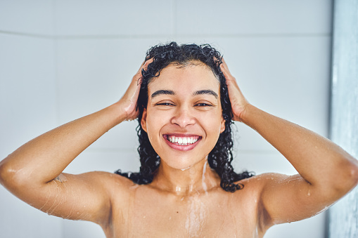 Portrait of an attractive young woman taking a shower inside her bathroom at home
