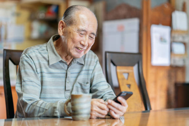 Portrait of senior man while using smart phone A portrait of a senior adult man while using a smart phone at home. 80 89 years photos stock pictures, royalty-free photos & images