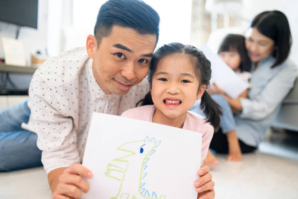 istock Asian father and daughter holding up a drawing 1181654219