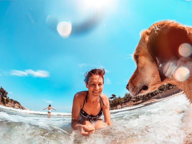 Woman playing with her small yellow dog at the beach