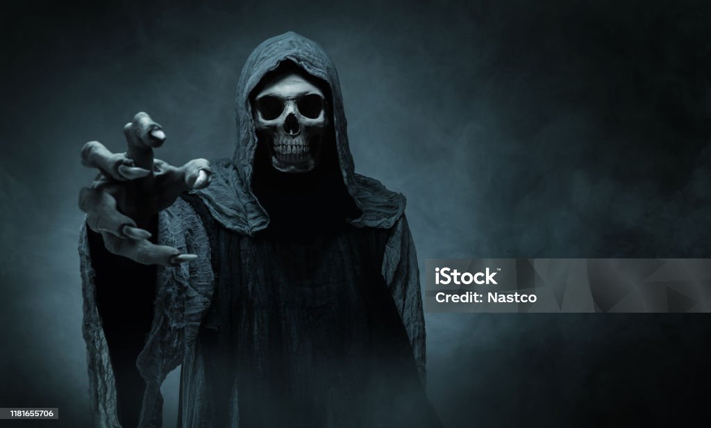 Grim reaper reaching towards the camera Grim reaper reaching towards the camera over dark misty background with copy space Spooky Stock Photo