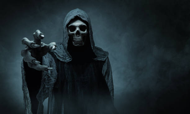 Grim reaper reaching towards the camera Grim reaper reaching towards the camera over dark misty background with copy space human skull stock pictures, royalty-free photos & images