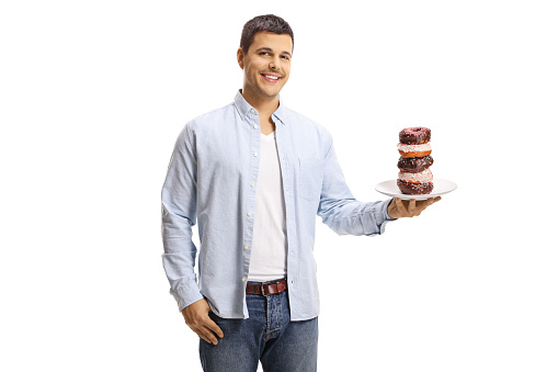Young man holding a plate of donuts and smiling isolated on white background