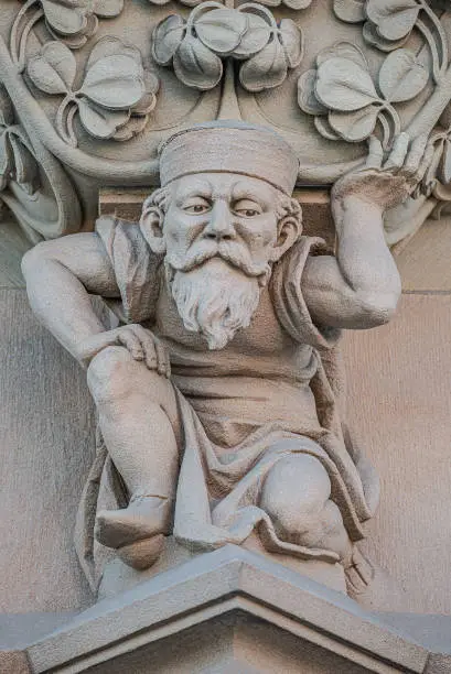 Photo of Sculpture of an old small and bearded funny man, dwarf, as an atlant in downtown of Magdeburg, Germany, closeup, details