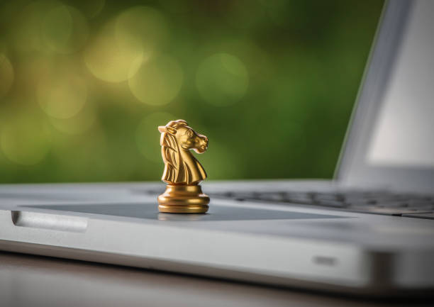 Online strategy, online marketing or business strategy concept. Golden chess knight is on laptop with bokeh background (depth of field photography). stock photo