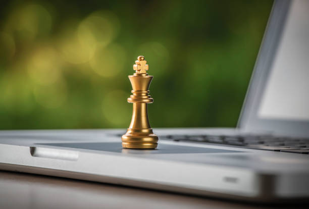 Online strategy, online marketing or business strategy concept. Golden chess king is on laptop with bokeh background (depth of field photography). stock photo