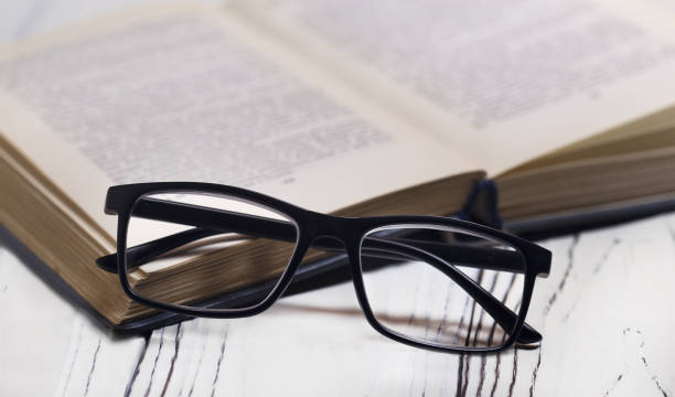 istock Glasses and a book on a wooden table. Vision problems. 1181656934