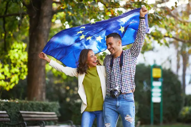 Photo of Happy young couple of tourists with a European Union flag
