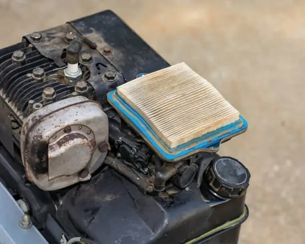 Photo of Dirty air filter on small gas engine of garden tiller. Concept of home dyi maintenance, tune-up, and repair