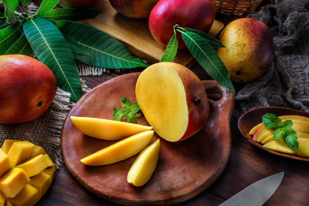 istock Tropical Fruits: Sliced mangos in a clay rustic plate on a wooden table in rustic kitchen 1181659359