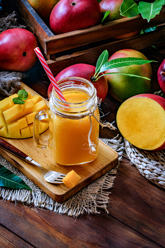 Healthy eating themes. Tropical fruits. Mango smoothie  juice and fruit un drinking glass on wooden table in rustic kitchen