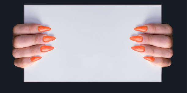 istock Woman with orange stiletto nails holding a whiteboard with copy space 1181663165