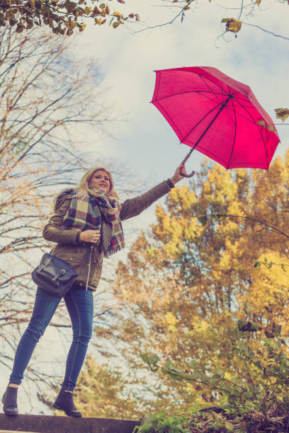 istock Woman walking in park with umbrella, strong wind 1181663767