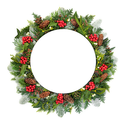 Christmas table setting with round plate, holly and winter flora and fauna on whte background with copy space.