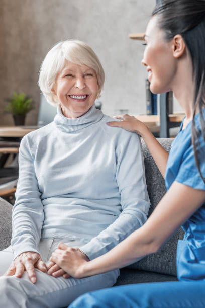vertikale aufnahme von hilfreichen krankenschwester kümmert sich um seniorin im pflegeheim - arzthelferin fotos stock-fotos und bilder