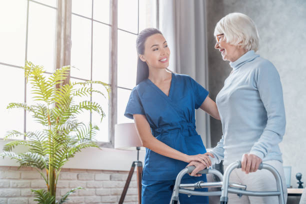 młoda pracownica socjalna pomagająca starszej kobiecie chodzić z walkerem w domu - nursing home senior adult home caregiver physical therapy zdjęcia i obrazy z banku zdjęć