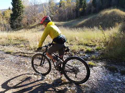 Asian guy with a red helmet riding a bike around Sardine Peak Trailhead, Ogden, Utah, United States. In motion photo.