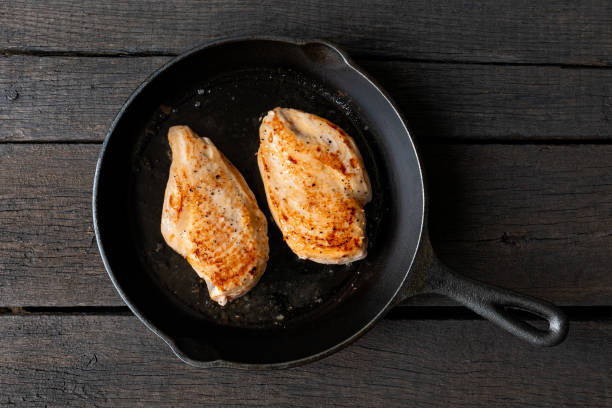 due seni di pollo interi arrostiti in padella di ghisa isolati su legno scuro. vista dall'alto. - chicken pot foto e immagini stock