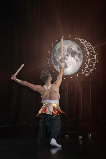 Taiko drummer hits the big drum full moon on stage on a black background, back view. Elements of this image furnished by NASA.

/url: https://images.nasa.gov/details-GSFC_20171208_Archive_e000868.html
