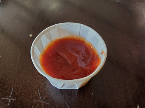 Close-up of a paper condiment cup with ketchup in a restaurant, October 14, 2019