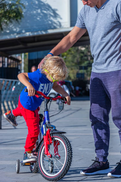 istock Father helping son climb on bicycle 1181681363