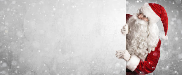 istock Santa Claus Showing Something On a White Wall 1181681470