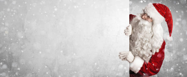 Santa Claus Showing Something On a White Wall Santa Claus Holding Blank Advertisement Banner Background with Copy Space reduction photos stock pictures, royalty-free photos & images