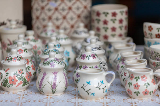 Vibrant handmade pottery with floral and fruit motifs displayed under sunlight at an outdoor market. Traditional ceramic art showcasing vivid craftsmanship and Mediterranean decorative style.