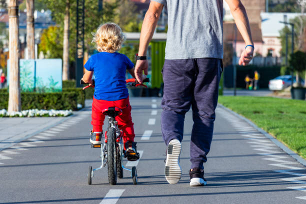 istock Father walking with son on a bike 1181682624