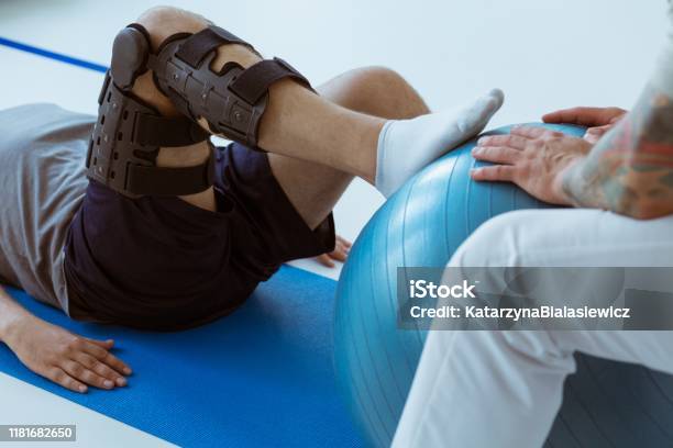 Pretty Patient Sitting On The Blue Mat In The Gym And Training With The Ball Stock Photo - Download Image Now