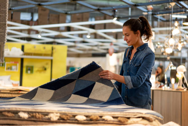 istock Female adult client at a home store looking at carpets on stack 1181690857