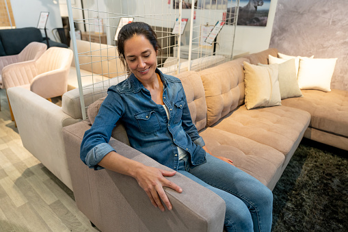 Happy female customer trying out a couch at a home store smiling - Lifestyles
