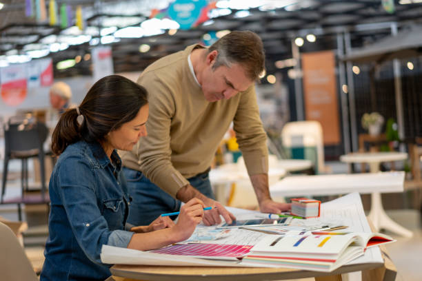 istock Focused creative couple working on a home renovation using a tablet, sketches and color swatches at a home store 1181691110