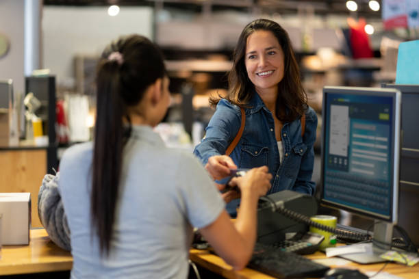 명랑한 여성 고객이 가구 가게에서 신용 카드로 비접촉식 결제를 하고 미소짓고 있습니다. - department store 뉴스 사진 이미지
