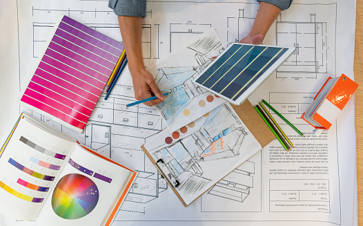 Unrecognizable interior designer working on a home renovation sketch while holding a tablet - High angle view