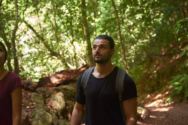 istock Young man looking up at the trees in a forest 1181691361