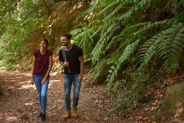 istock Couple laughing and talking as they walk by trees 1181692333