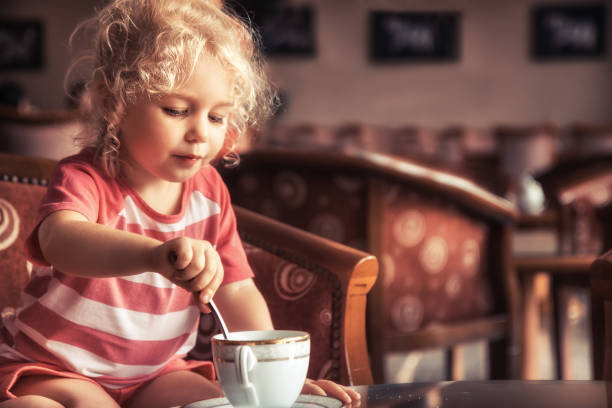 fille heureuse d'enfant buvant le thé dans le restaurant intérieur anglais traditionnel classique - five oclock tea photos et images de collection